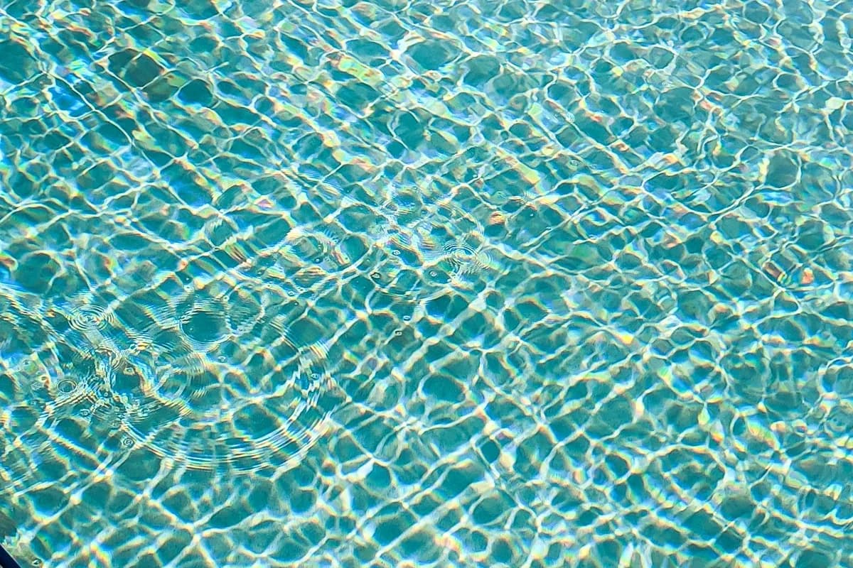 Close-up of clear turquoise pool water with soft surface ripples in bright sunlight