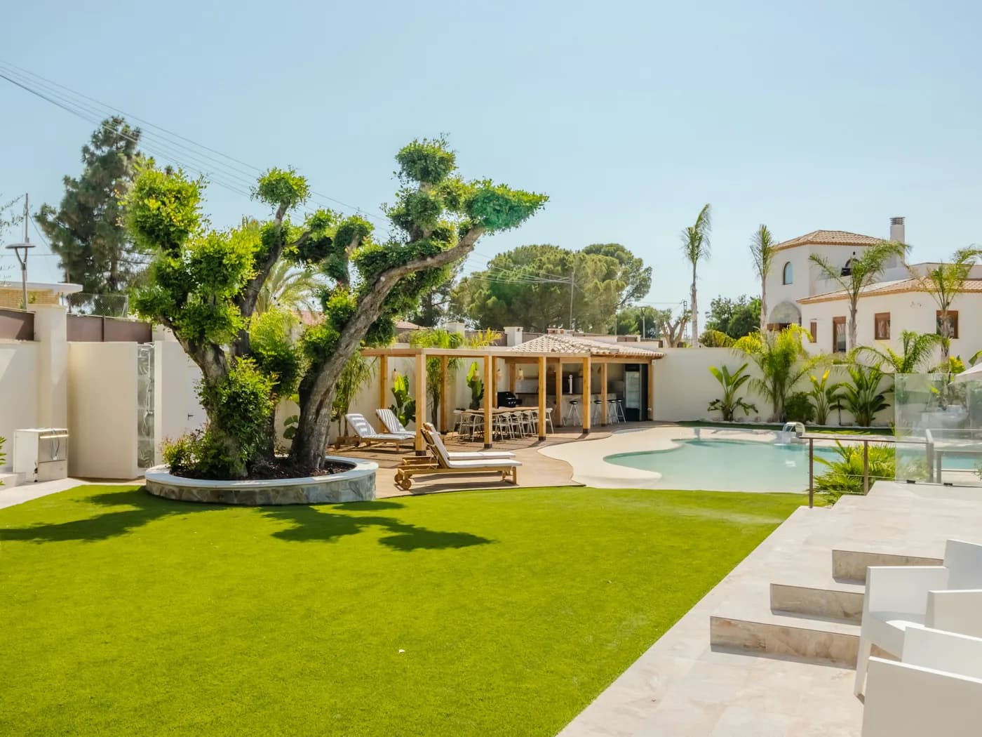 Premium backyard with geometric pool, travertine steps, lawn, and shaded pergola lounge