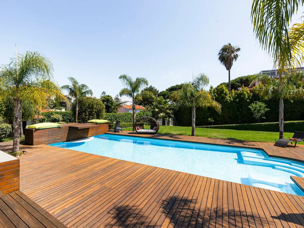 Clean geometric backyard pool with bright turquoise water and wood deck in full sun